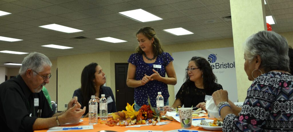 A group of Triple P practitioners seated at a table speak amongst each other.